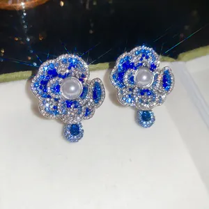 Macro detail of elegant blue crystal flower stud earrings featuring a white central pearl