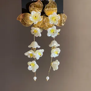 Detailed view of vintage-style floral tassel earrings with gold petals and white flower charms