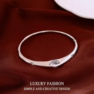 Elegant silver-toned bangle with sparkling marquise zircon stones on luxury red silk backdrop