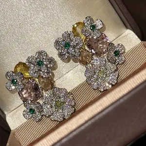 Close-up of sparkling zircon flower earrings with multi-colored gemstones in a gift box