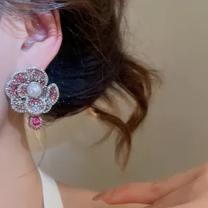 Close-up of elegant pearl flower earrings with pink crystal embellishments on model's ear