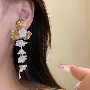 Elegant flower tassel earrings with golden petals and pearl detail in detail view