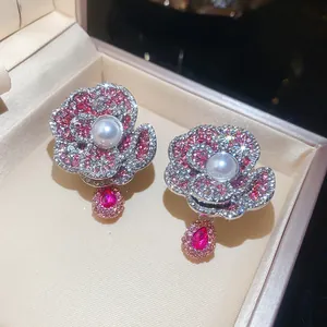 Detailed macro view of camellia flower earrings with pink rhinestones and central pearls