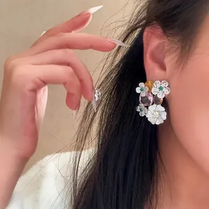 Close-up view of sparkling flower stud earrings with colorful cubic zirconia gemstones.