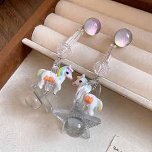 Cute resin unicorn earrings with glitter star charms on a velvet jewelry display.