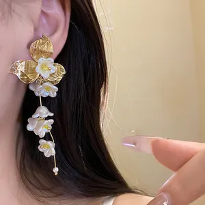 Elegant vintage gold flower earrings with white pearl tassels worn on a model's ear
