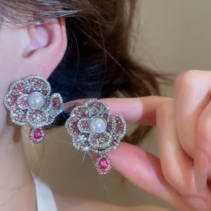 Close-up of retro flower-shaped earrings with pearls and pink crystals shown on an ear