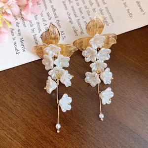 Elegant gold-tone floral tassel earrings with white resin flowers and pearl accents.