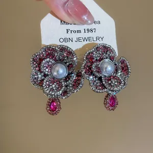 Close-up of pearl flower stud earrings with pink rhinestones and teardrop crystals