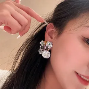Detailed close-up view of sparkling zircon flower and oval earrings on model's ear