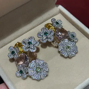 Detailed close-up of sparkling floral stud earrings with multi-color crystals in a beige box.