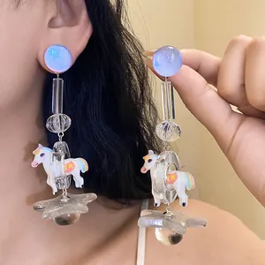 Detailed shot of resin dangle earrings with blue glitter studs and carousel horse charms