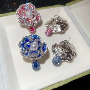 Detailed view of sparkling flower stud earrings with center pearls and elegant teardrop charms