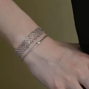 Close-up of minimalist metal mesh and thin chain bracelets on a wrist