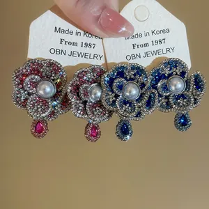 Close-up of retro pearl flower earrings with colorful rhinestones on display cards.