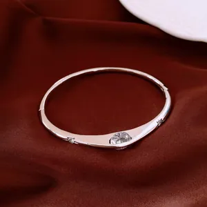 Close-up of elegant vintage style silver zircon bangle on smooth red silk fabric