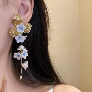 Detail of vintage gold floral tassel earrings with pearl and blue accents on ear