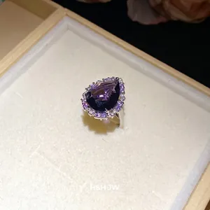 Luxury pear-shaped dark purple zircon ring with sparkling halo in a jewelry box display.