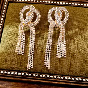 Sparkling rhinestone knot tassel earrings with gold-tone finish on green velvet