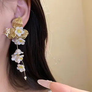 Elegant gold and white vintage floral tassel earrings shown as close-up detail on ear