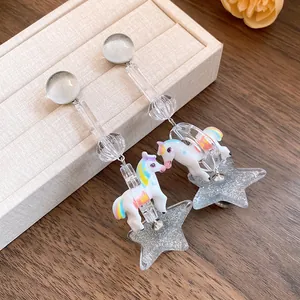 Detailed view of whimsical resin unicorn and glitter star earrings with silver needles.