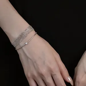 Detailed view of silver metal mesh bracelet and delicate single stone chain on wrist