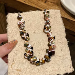 Vintage irregular shell necklace featuring natural spiral elements on rustic handmade paper