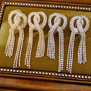 Macro view showing details of sparkling rhinestone knotted tassel earrings on green velvet background