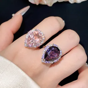 Detailed close-up of elegant pear-cut pink and purple zircon rings worn on a hand model.