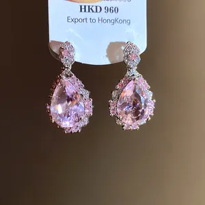Detailed close-up of elegant pink pear-cut zircon drop earrings on a white display card.