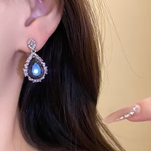 Detailed close-up of an elegant teardrop zircon earring featuring a stunning dark blue gemstone