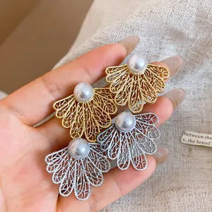 Primer plano detallado de elegantes pendientes de perlas calados en oro y plata