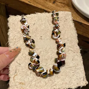 Macro view of retro spiral shell necklace showing natural textures and earthy tones.