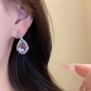 Close-up of elegant pink teardrop zircon earrings worn on ear with sparkling accents