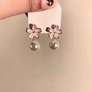 Close-up of sweet pink flower earrings with hanging pearls on a white display card