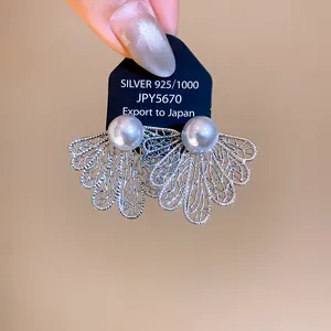 Primer plano de pendientes de hoja hueca con perlas en tarjeta de joyería negra