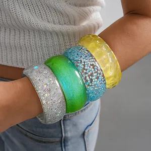 Detailed shot of stacked colorful chunky resin bangles on a female model arm.