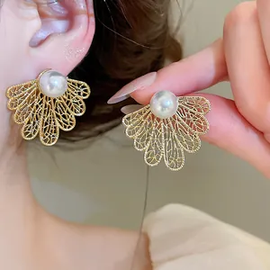 Primer plano detallado de elegantes pendientes de perlas con hojas doradas huecas