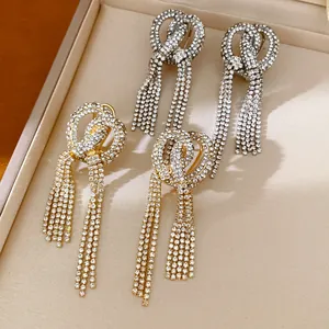 Detailed view of silver and gold rhinestone knotted tassel earrings on jewelry tray