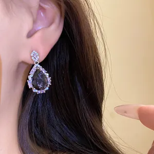 Detailed close-up of a sparkling teardrop earring with black zircon and halo setting