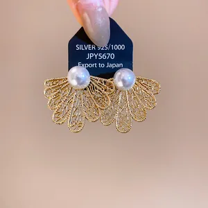Detalle de los pendientes de hoja dorada hueca con perlas y base de plata 925