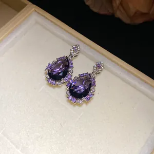 Detailed macro view of elegant pear-shaped purple zircon earrings with sparkling halo