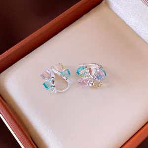 Close-up detail of silver earrings with clustered colorful square-cut gemstones in a box