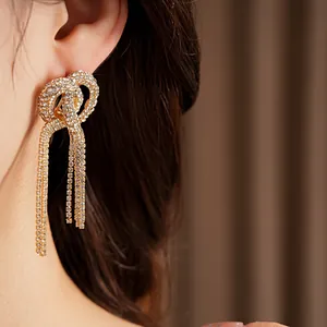 Detailed close-up view of elegant rhinestone knotted crossover tassel earrings on ear