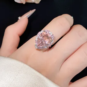 Close-up detail of a luxury pear-shaped pink zircon ring showcased on an index finger.