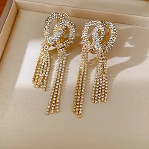 Macro detail of elegant gold tassel earrings with intricate knot design and sparkling rhinestones