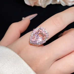 Detail showing large pear-shaped pink zircon ring on finger with halo stones.