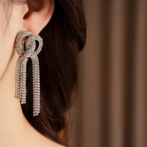Detailed close-up view of elegant sparkling rhinestone bow-knot tassel earrings worn on ear