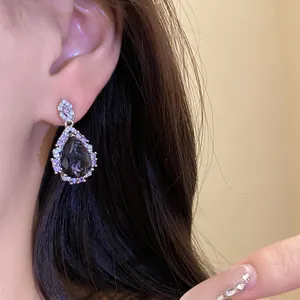 Elegant teardrop earring with dark gemstone and shimmering zircon halo detail shot