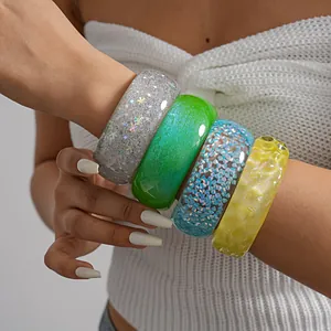 Close-up of colorful chunky resin bangles with glitter and holographic details